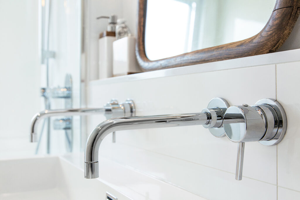 Gros plan sur la robinetterie du lavabo de la salle de bains de la résidence au design intérieur conçu par les designers intérieur de Clairoux. Close-up of the faucet on the bathroom sink in the residence, with interior design created by Clairoux’s interior designers.