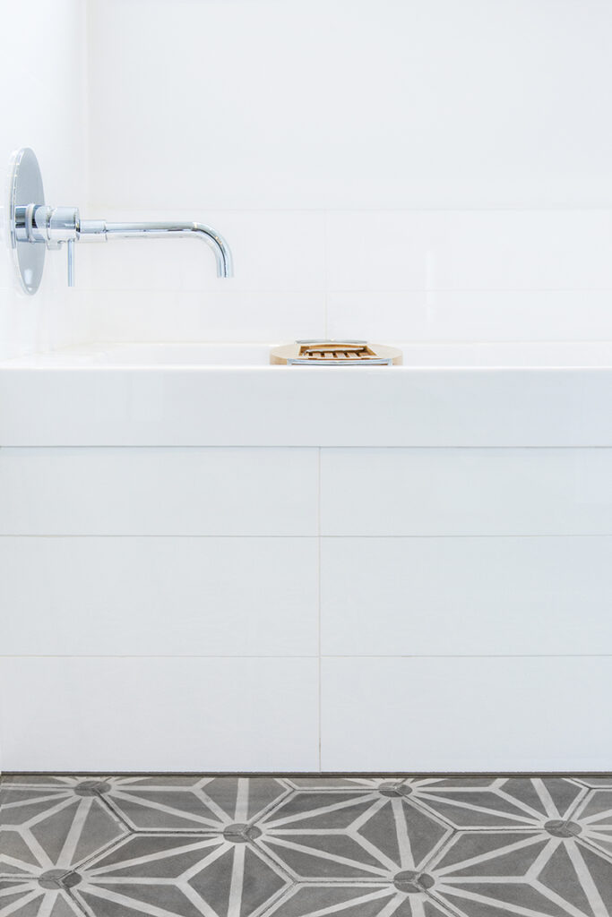 Gros plan du bain montrant également le plancher en céramique et le fini du côté du bain ainsi que la robinetterie moderne. Close-up of the bathtub also showing the ceramic flooring, the bathtub side finish, and the modern faucet.