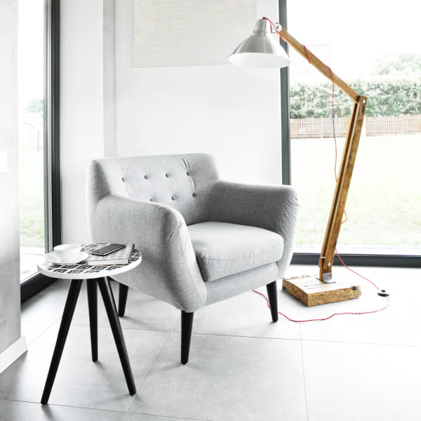Chaise grise et lampe devant une fenêtre.