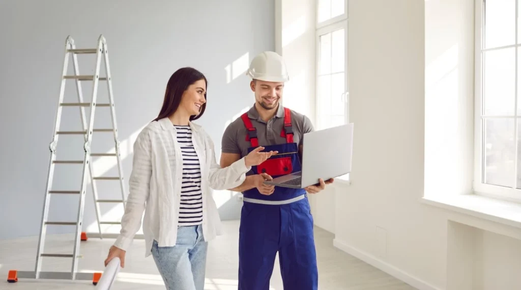Two people renovating a room watching a laptop